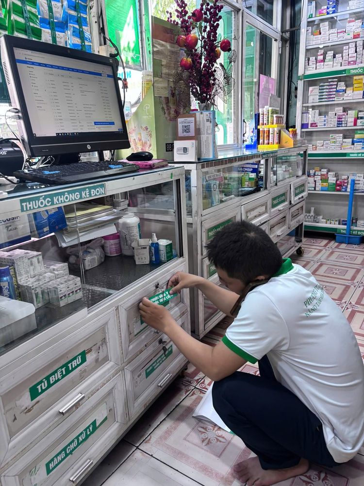Nhân viên dán nhãn khu vực thuốc trên tủ quầy