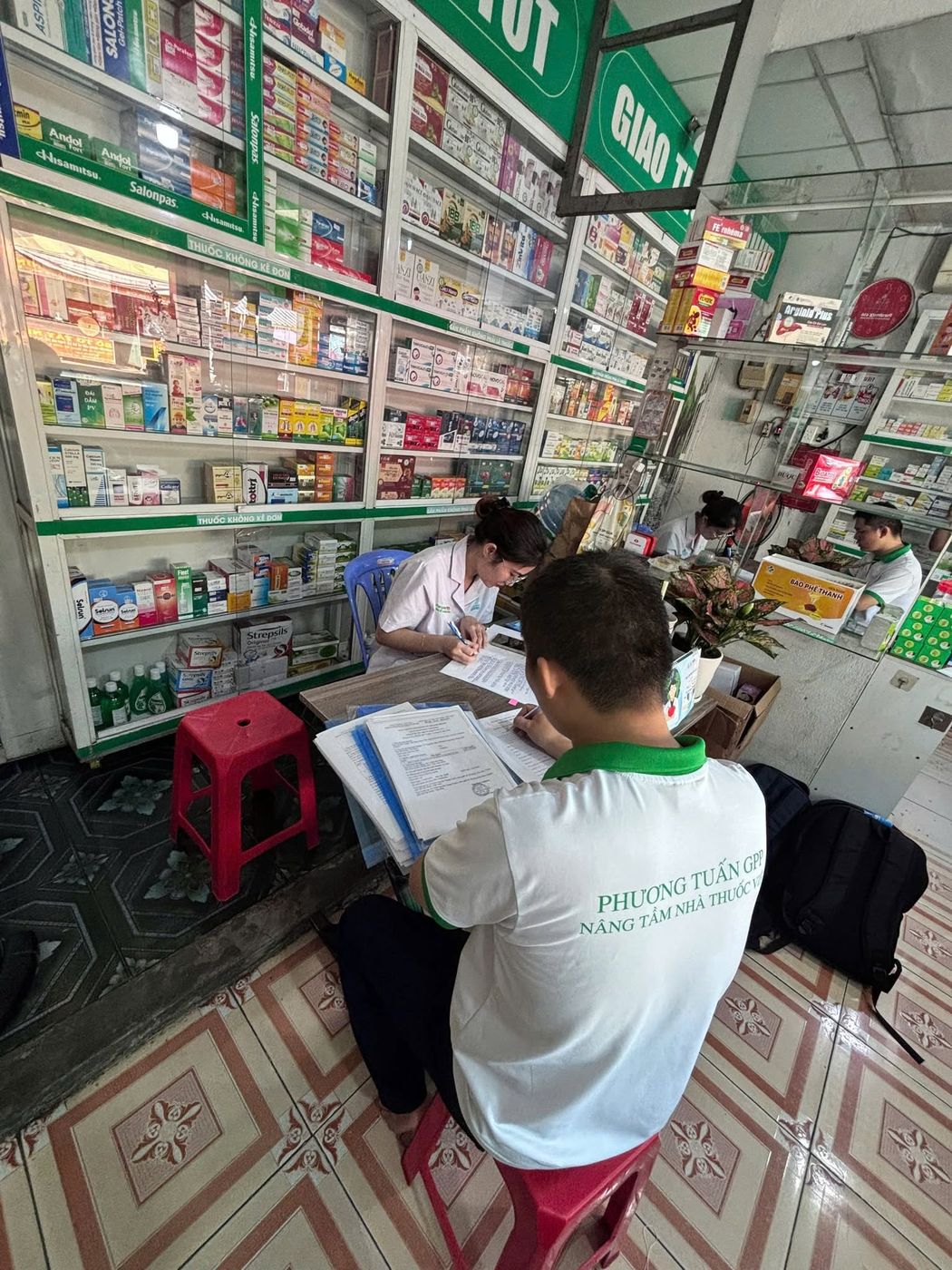 Nhân viên Phương Tuấn GPP ngồi rà hồ sơ giữa các tủ thuốc của một nhà thuốc